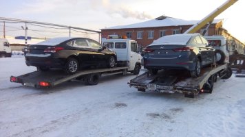 Два эвакуатора RaceExpress перевозят новые автомобили в автосалон Hyundai в Тюмени